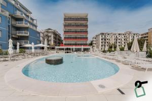 una grande piscina con sedie e un edificio di HOTIDAY Hotel Jesolo Spiaggia a Lido di Jesolo