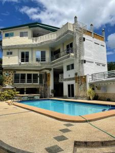 a house with a swimming pool in front of a building at Elicon Suites in Tagbilaran City