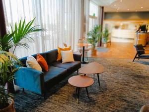 a living room with a blue couch and two tables at Future Inn Cardiff Bay in Cardiff