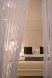 a white bed with black pillows behind a curtain at Lesic Dimitri Palace in Korčula