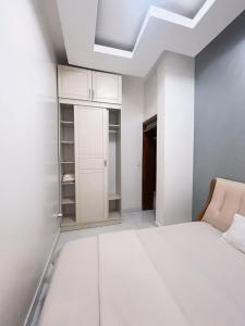 Kigali Highland Paradiso في كيغالي: غرفة نوم بيضاء مع سرير وخزانة