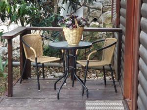 a table with two chairs and a basket of flowers on a porch at Zimmer In The Garden in Karmiel
