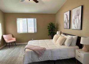 um quarto com uma cama branca e uma cadeira rosa em Summer Individual Community Villa em San Gabriel