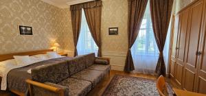 Zamecky Hotel Lednice في ليدنيس: غرفه فندقيه بسرير واريكه