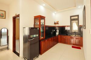 a kitchen with a stainless steel refrigerator and wooden cabinets at Sen Đá Villa - Succulent Villa in Da Lat