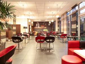 a restaurant with red and black chairs and tables at Ibis Styles Abidjan Plateau in Abidjan