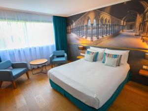 um quarto de hotel com uma cama e uma cadeira em Mercure Mont Saint Michel em Monte Saint-Michel