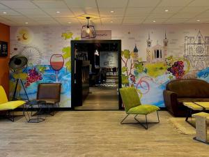 a waiting room with chairs and a colorful wall at Mercure Lyon Est Chaponnay in Chaponnay