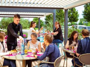 un groupe de personnes assises à une table avec des verres à vin dans l'établissement Mercure Lyon Est Chaponnay, à Chaponnay