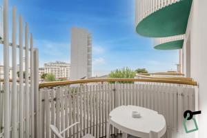 un balcón con una mesa y una silla blancas y un edificio en HOTIDAY Hotel Jesolo Lido, en Lido di Jesolo