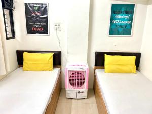two beds in a room with a fan at Procida Hostel by Zero Jhanjhat in Pune