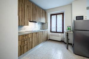 a kitchen with wooden cabinets and a stainless steel refrigerator at Appartamento Squarà - con Vista Cascata, vicino Verona in Montorio Veronese