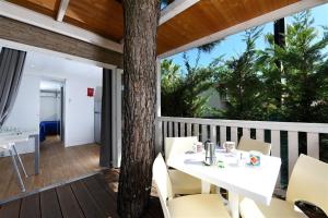 eine Veranda mit einem Tisch, Stühlen und einem Baum in der Unterkunft Don Antonio Glamping Village in Giulianova