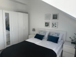 a white bedroom with a bed with blue pillows at Departaapartamenty - Port - Towarowa 5 in Kołobrzeg