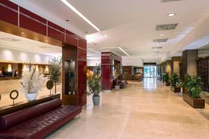 um lobby de um hotel com um sofá e vasos de plantas em NH Vienna Airport Conference Center em Schwechat