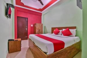 OYO Hotel Happy Journey في Dīgha: غرفة نوم بسرير كبير وبجدران حمراء