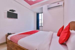 a bedroom with a bed with red pillows and a tv at OYO Hotel Happy Journey in Dīgha