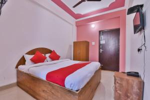 OYO Hotel Happy Journey في Dīgha: غرفة نوم بسرير ومخدات حمراء وتلفزيون