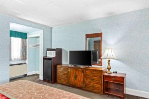 una camera da letto con TV a schermo piatto su un comò in legno di Rodeway Inn Historic a Williamsburg