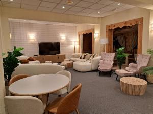 a living room with couches and chairs and a tv at Hôtel Espace Montclar in Montclar