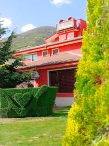 una casa rossa con una siepe davanti di Хотел-ресторант Алмонд a Karlovo