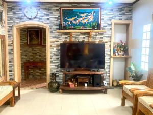 sala de estar con TV de pantalla plana en una pared de ladrillo en Baguio mountain villa view RW en Baguio