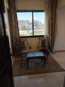 duas cadeiras e um banco num quarto com uma janela em New Siesta Hotel & Resort em Alexandria
