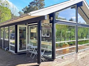 a house with large windows and a table and chairs at 8 person holiday home in Hadsund in Hadsund