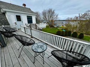 a deck with chairs and a table and a fence at The Harpswell Inn in Harpswell Center