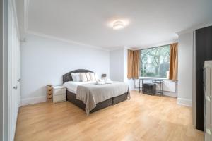 Dormitorio blanco con cama y ventana grande en Luxury St Johns Wood 2-bed with 24hr Concierge, en Londres