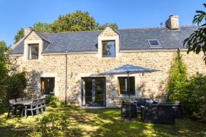 a brick house with a table and an umbrella at Les gîtes du Plec - Piscine in Locoal-Mendon