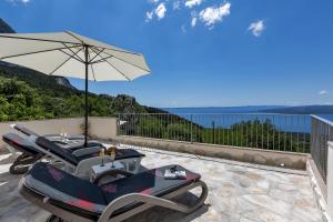 a patio with a table and chairs and an umbrella at Holiday home Marta with heated pool,grill,sea view in Bast