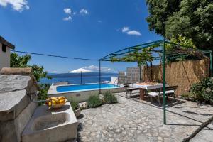 a patio with a table and a swimming pool at Holiday home Marta with heated pool,grill,sea view in Bast
