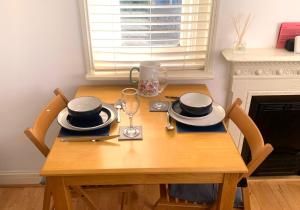 a wooden table with plates and glasses on it at Old School Apartment 1 First Floor in Bury Saint Edmunds