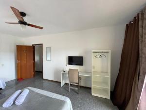 a bedroom with a bed and a desk with a tv at Pousada aconchegante in Jequié