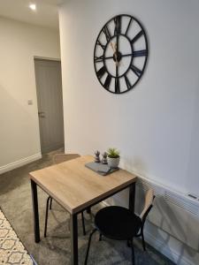MytholmroydにあるCosy 1 Bedroom Apartmentの椅子付きテーブル、壁掛け時計