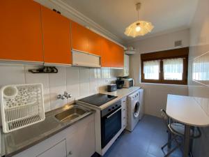 a kitchen with orange cabinets and a sink and a dishwasher at Increíbles Vistas a la Ría de Mogro in Miengo