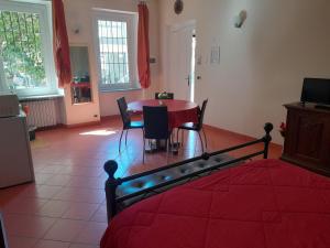 un soggiorno con tavolo e letto rosso di "B&B Sans égal", con camere private e appartamenti al piano terra a Biella a Biella