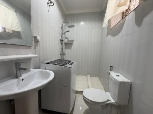 a white bathroom with a toilet and a sink at Mokawa BnB Stone Town in Ngambo