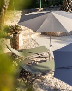 two lawn chairs and an umbrella on a patio at MASHTRA - The Olive House in Ulcinj