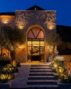 un edificio in pietra con una grande porta a vetri di notte di MASHTRA - The Olive House a Ulcinj