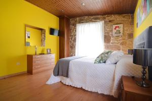 a bedroom with a bed with yellow walls and a window at GALIHOST - Casa da Sobreira in Meis