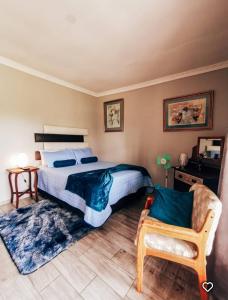 een slaapkamer met een bed en een stoel bij Midvaal Guesthouse in Meyerton