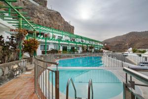 a hotel with a swimming pool next to a mountain at Casa Los Veleros F1 in Puerto Rico de Gran Canaria
