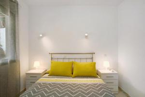 a bedroom with a bed with two night stands and two yellow pillows at Casa Los Veleros F1 in Puerto Rico de Gran Canaria +22 photos