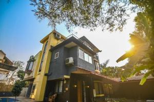a yellow and black house with a tree at Misty Palace Luxury Villa by Natura Stays in Lonavala