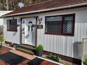 Casa pequeña con puerta blanca y porche en The Old Forestry Cottage, en Portree