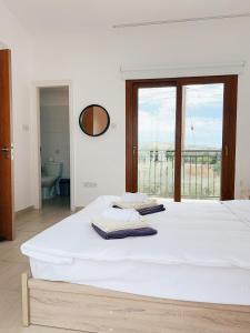 un letto bianco in una stanza con una grande finestra di White Mountain Pool Villas a Paphos