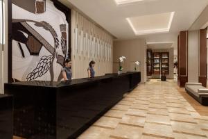 two people standing at a reception desk in a lobby at Chiang Mai Marriott Hotel in Chiang Mai
