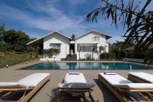 a house with a swimming pool with two lounge chairs at Grape County Eco Resort & Spa, Nashik in Nashik